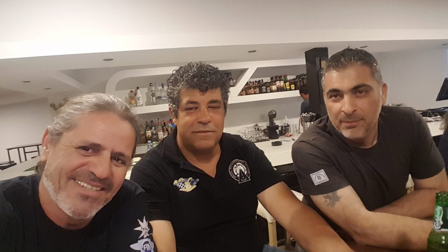 Τρεις φίλοι με μαύρα μπλουζάκια χαμογελούν στον πάγκο ενός μπαρ